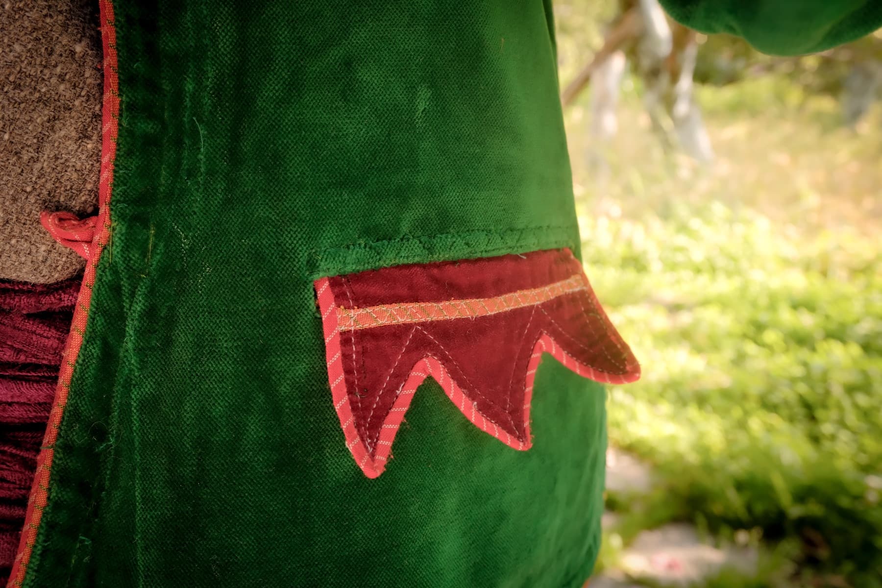 Green velvet jacket with a hand-stitched red pocket